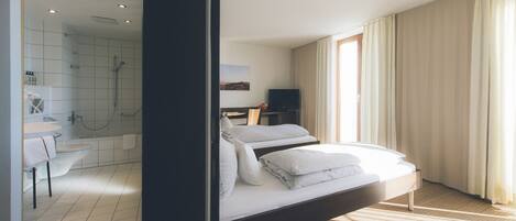 Une chambre d’hôtel moderne dotée d’un grand lit, d’une salle de bain avec douche et d’un téléviseur.