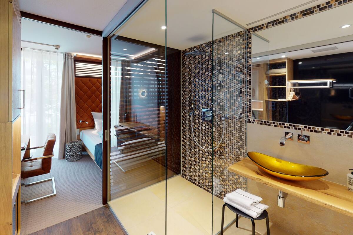 A modern bathroom with a glass partition, a yellow sink, and a mirrored wall.
