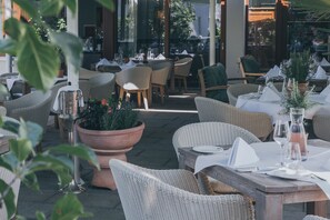 An outdoor dining area with wicker furniture, potted plants, and neatly set tables. - Das Wildeck (Abstatt)