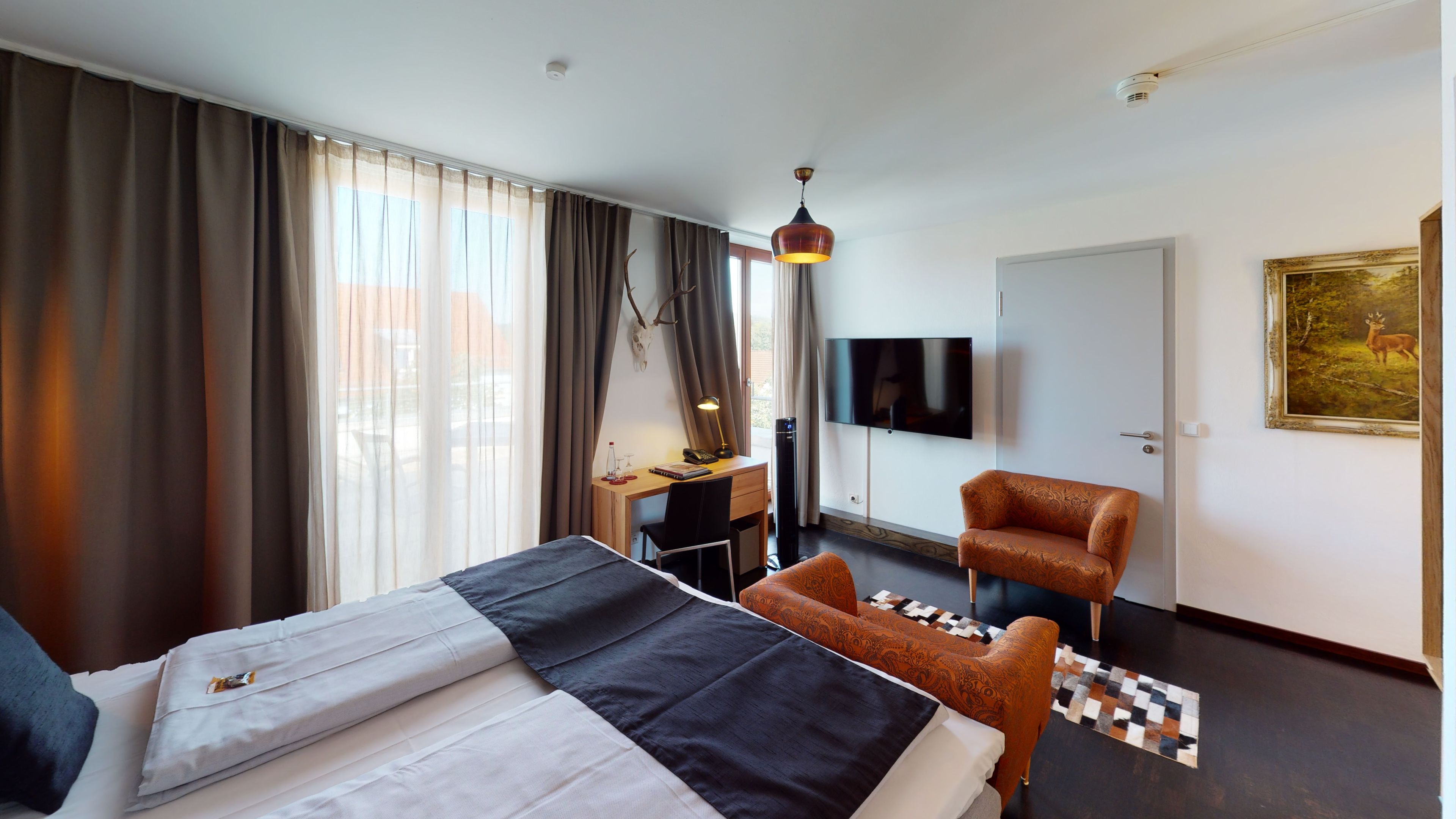 Een hotelkamer met een bed, een bureau, een stoel, een televisie en een schilderij aan de muur.