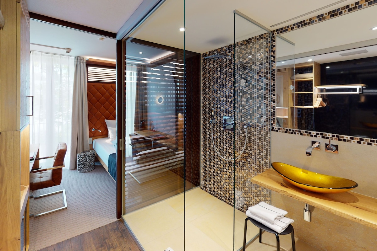 A modern bathroom with a glass partition, a yellow sink, and a mirrored wall.