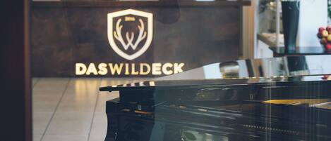 A grand piano in a room with a reception desk and a logo that reads 'DASWILDECK'.