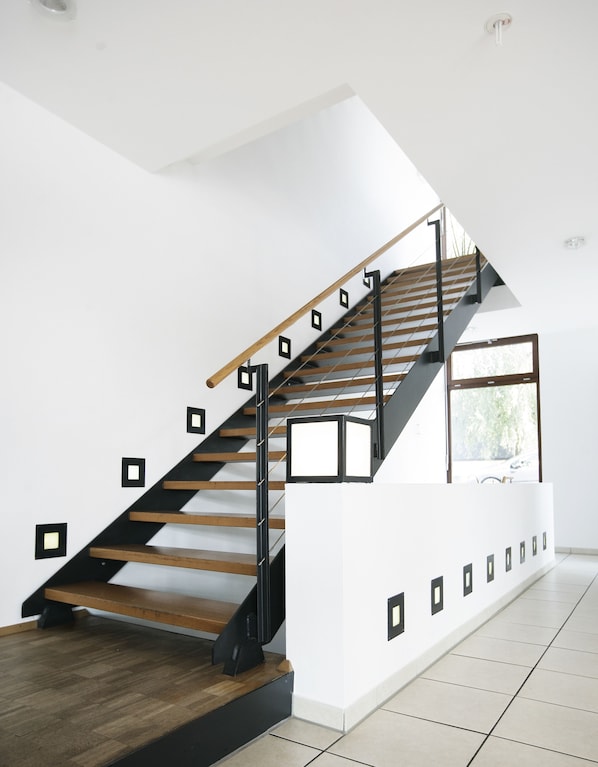 A modern staircase with wooden steps and black railings, leading to a landing with a window. - Das Wildeck (Abstatt)