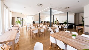 A spacious conference room with multiple tables and chairs, large windows, and a modern ceiling design. - Hôtel Atrium Mondial (Lourdes)
