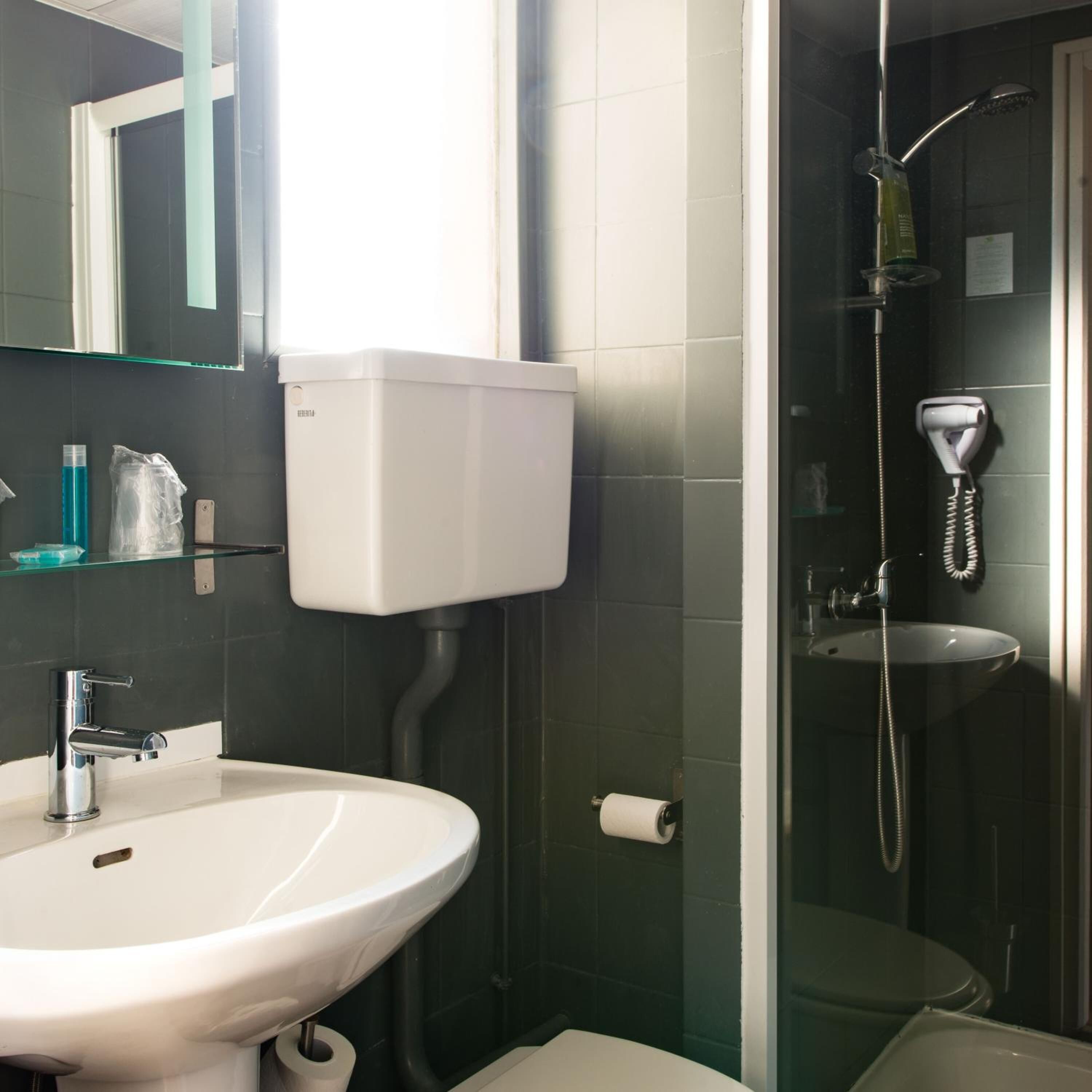 A bathroom with a white sink, a toilet, a glass shower enclosure, and a mirror above the sink.