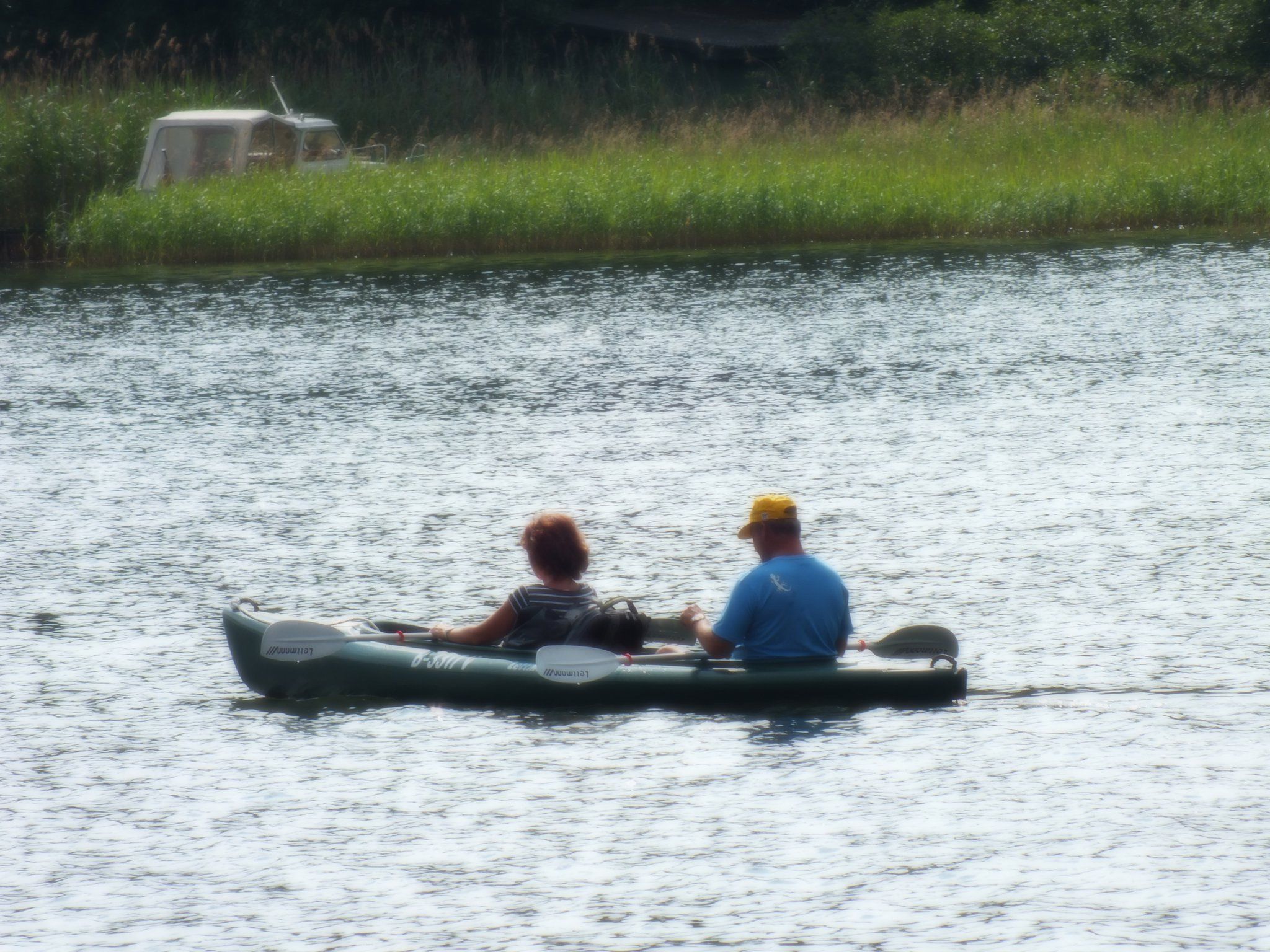 Twee personen in een groene opblaasboot op een kalm wateroppervlak.