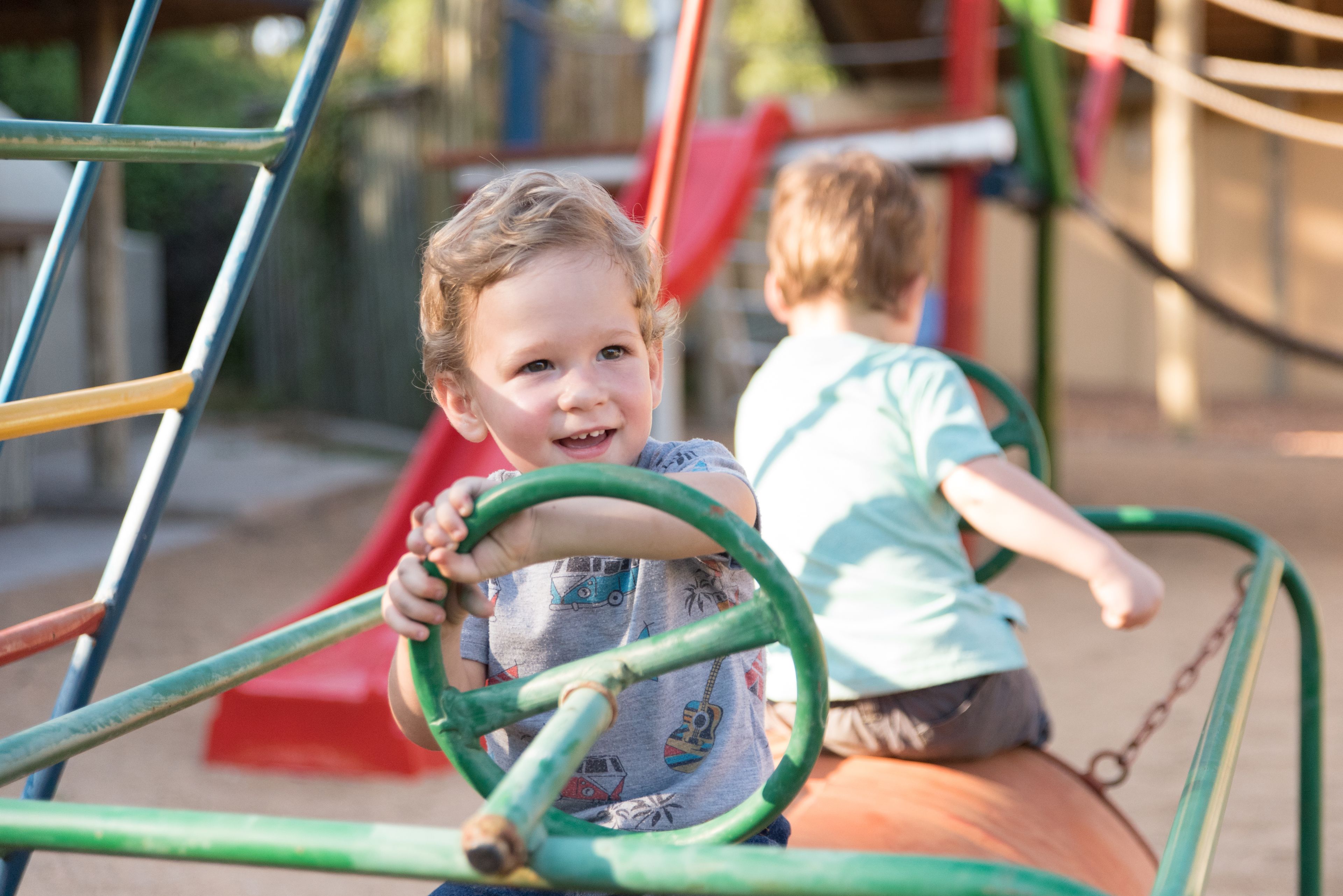 Un nen jugant en un parc infantil amb tobogan i elements per escalar.