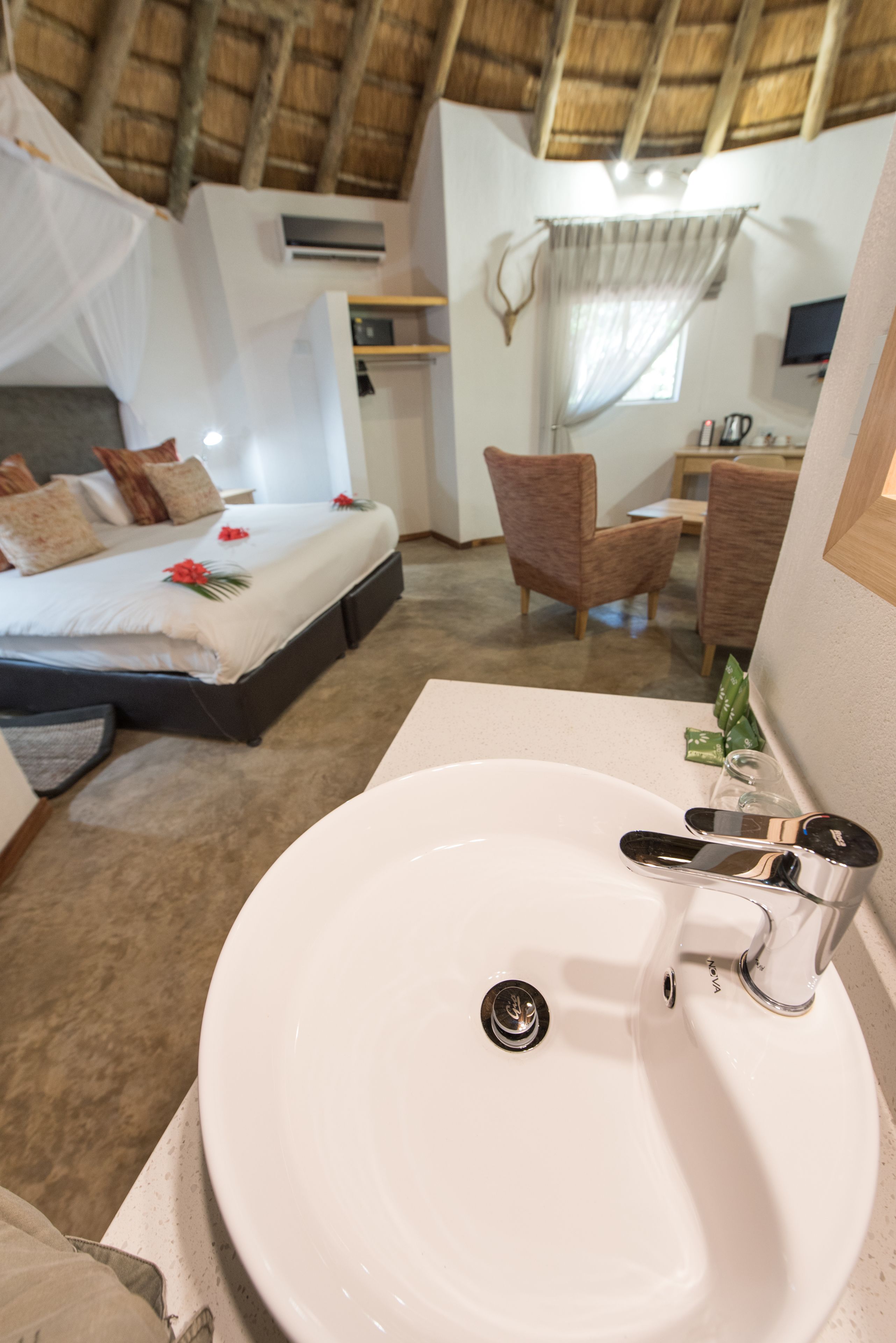 Een hotelkamer met een bed, een badkamer met een wastafel en een eethoek met stoelen.