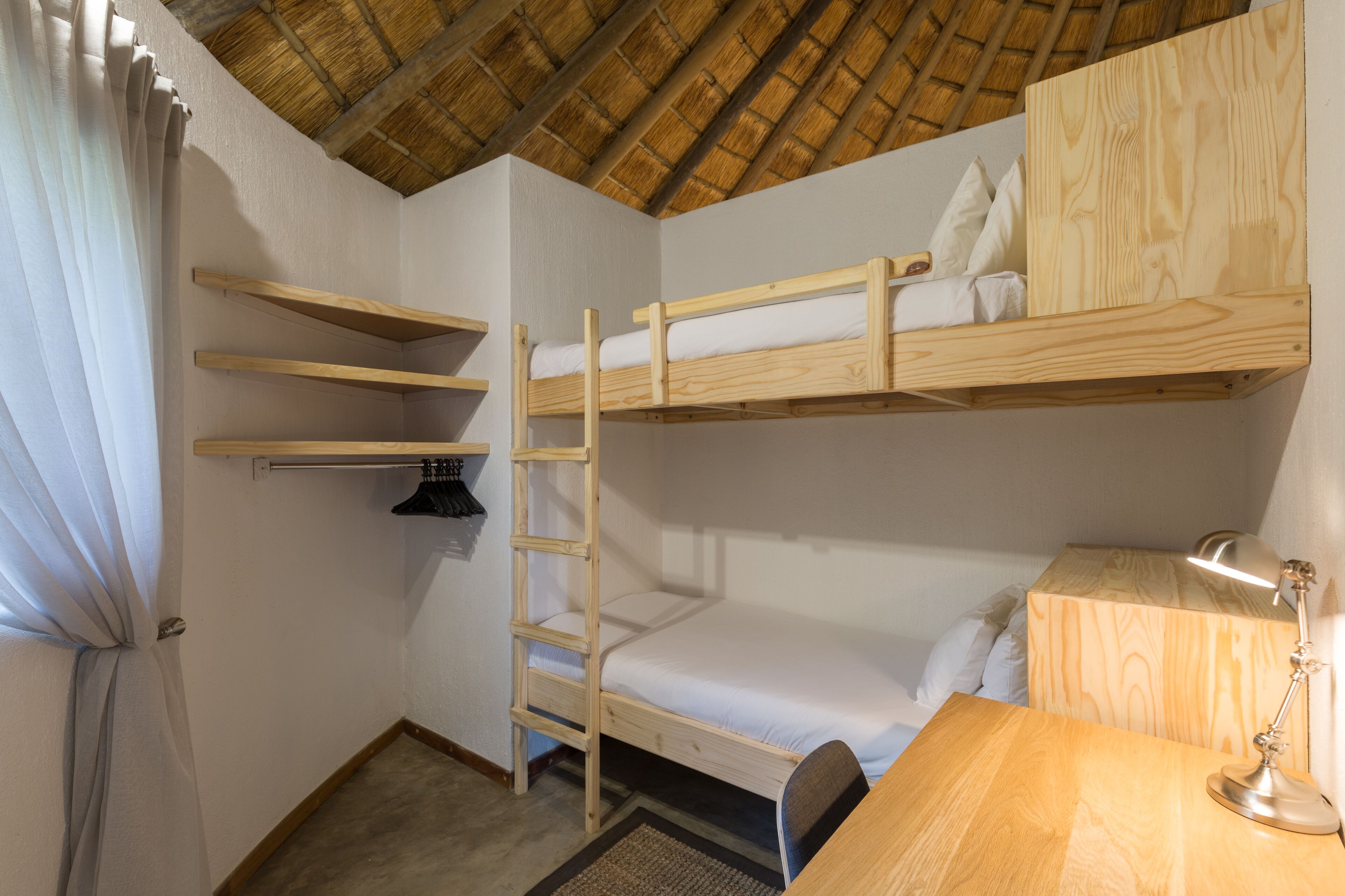 Ein kleines Zimmer mit Etagenbetten, einem Schreibtisch und einem Stuhl.