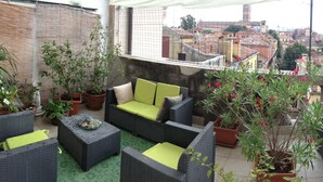 A rooftop terrace with wicker furniture, potted plants, and a view of the cityscape. - Ostello Domus Civica (Venice)