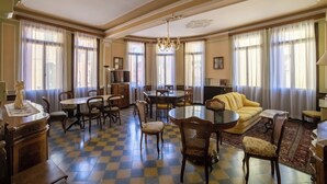 A spacious room with a checkered floor, a dining table, chairs, a sofa, and a chandelier. - Ostello Domus Civica (Venice)