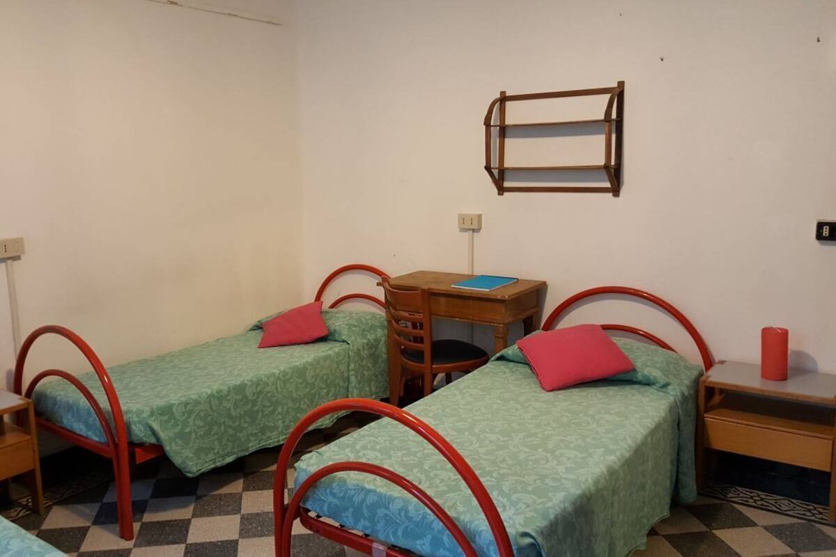 A dormitory room with two single beds, a desk, and a chair.