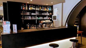 A bar area with a counter, stools, and shelves stocked with bottles and glasses.