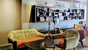 A modern lounge area with a sofa set, a coffee table, and a bookshelf filled with books and decorative items.