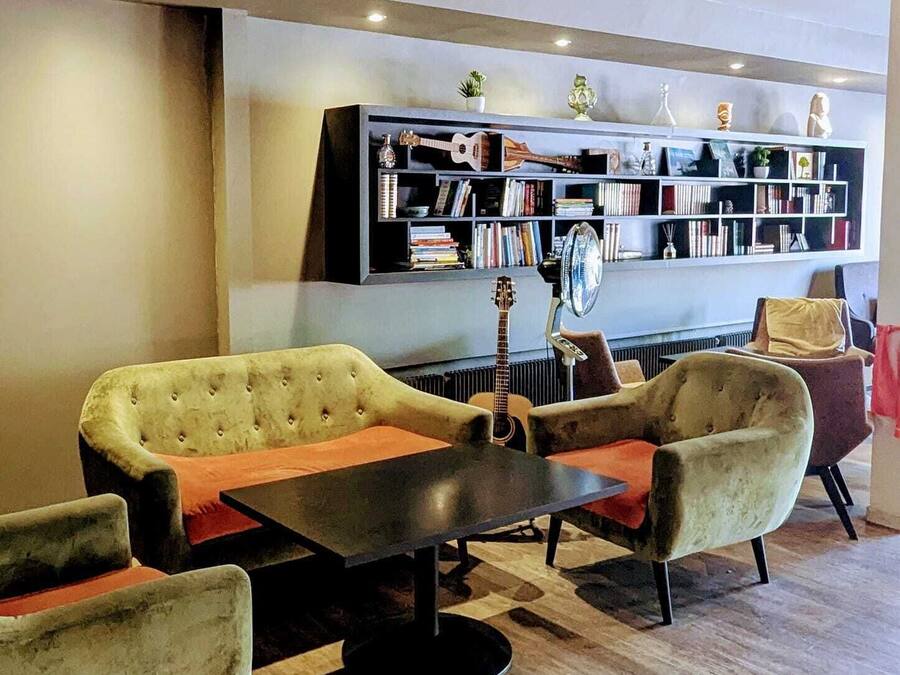 A modern lounge area with a sofa set, a coffee table, and a bookshelf filled with books and decorative items.