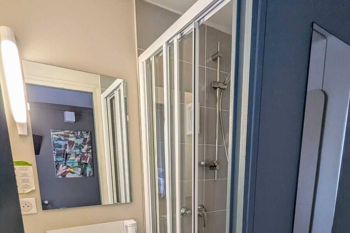 A modern bathroom with a glass-enclosed shower, a white sink, and a mirror above it.