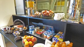 A buffet with various food items including fruits, pastries, and beverages.