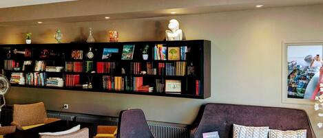 A modern lounge area with a bookshelf, seating, and a coffee table.