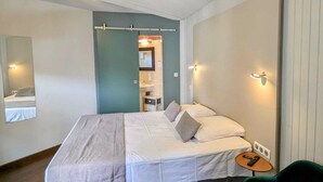 A bedroom with a bed, a bedside table, a chair, and a mirror.