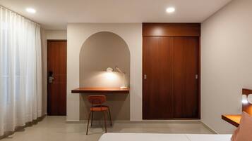 Hotelkamer met een bed, bureau met stoel, kast en deur naar de badkamer.