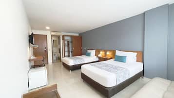 A hotel room with two beds, a desk, and a bathroom visible through an open door.