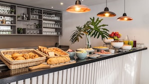 Un banco buffet con diversi cibi, un'area bar con bicchieri e lampade pendenti a sospensione.