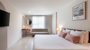 Camera d'albergo con un letto grande, una scrivania con una sedia, una TV a parete e un quadro incorniciato con vista sulla città.