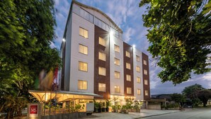 Un hotel moderno con tetto piano, numerose finestre e un'area ingresso ben illuminata con posti a sedere all'aperto.