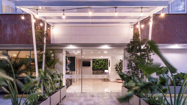 L'ingresso moderno di un edificio con porta in vetro, piante in vaso e luci a tendina.