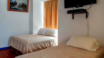 Dos camas con ropa de cama floral a juego, un cuadro de un paisaje montañoso y un televisor montado en la pared.