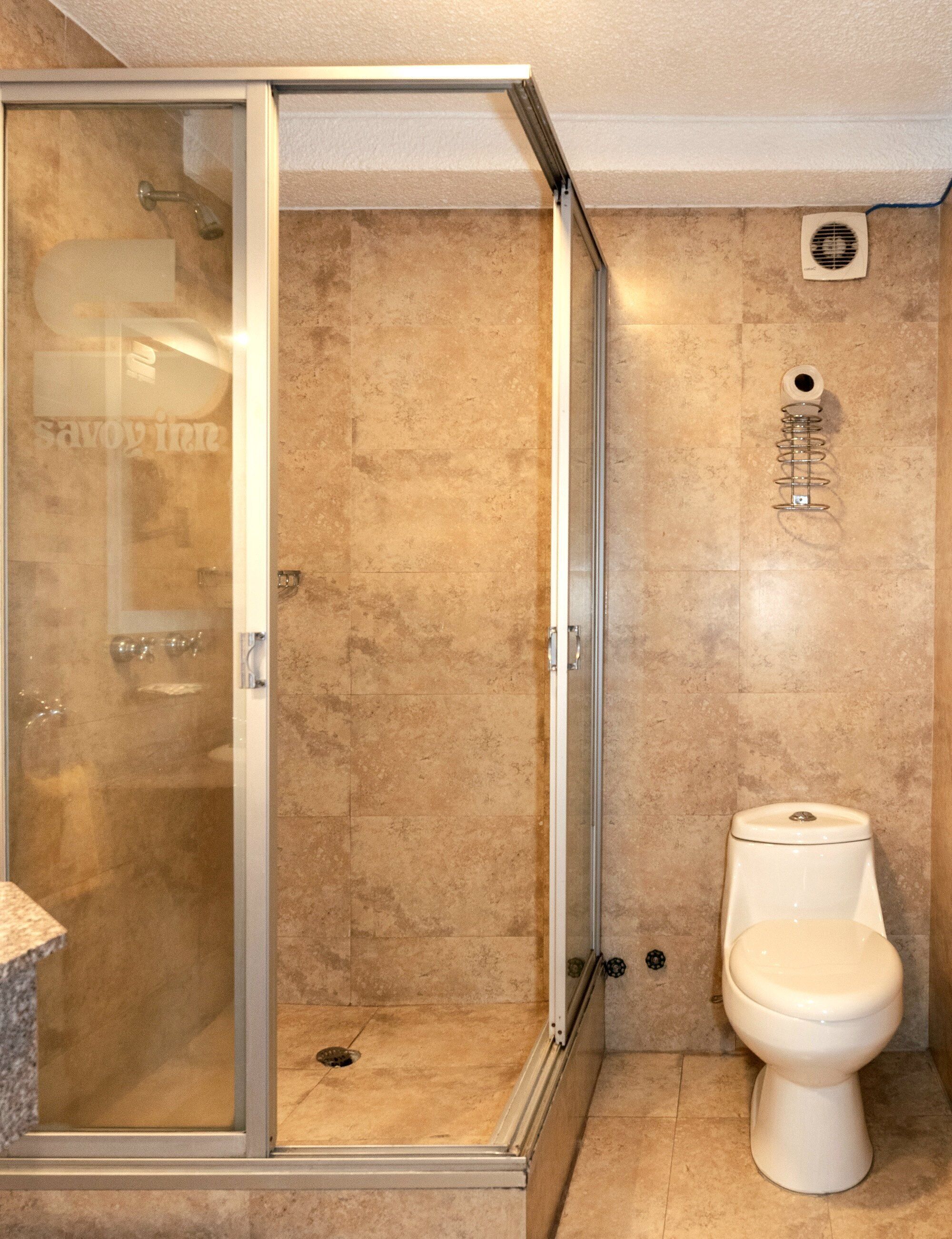 Un baño con ducha de vidrio, inodoro y suelo de mármol.