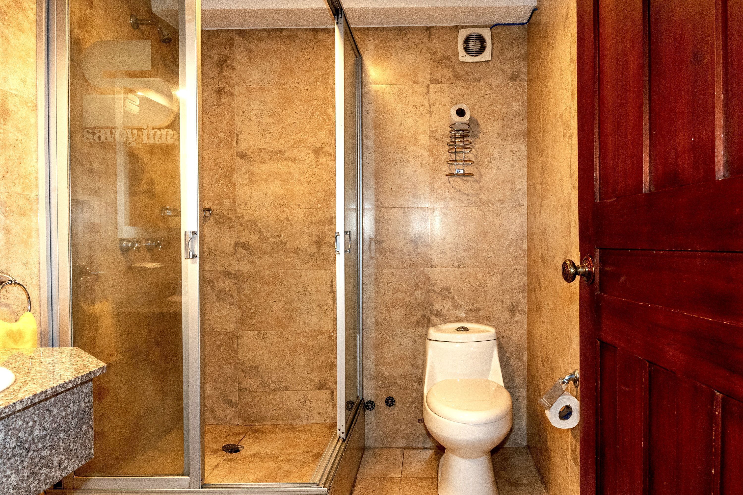 Een badkamer met een douchecabine van glas, een toilet en een wastafel.