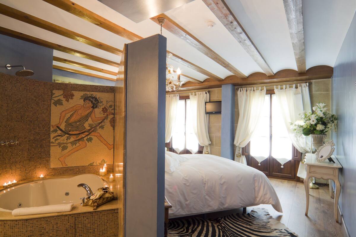 Une chambre avec un grand lit, une salle de bain avec une baignoire et une douche.