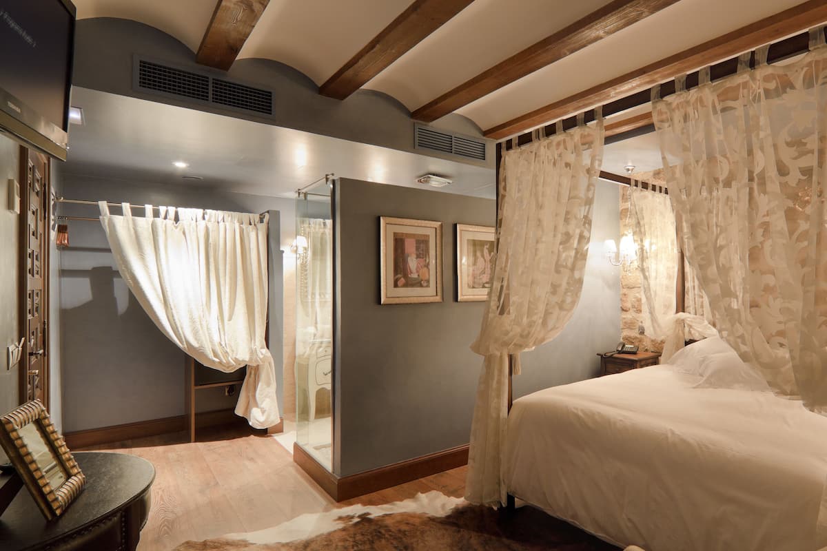 Une chambre à coucher avec un lit à baldaquin, un mur en pierre et un plafond en bois.
