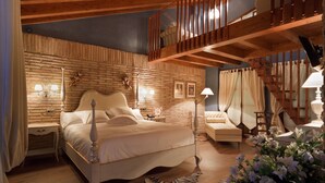 Une chambre avec un grand lit, un plafond en bois, un escalier et une vue sur l’extérieur.