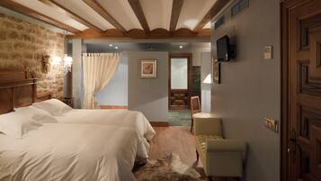 A bedroom with two beds, a wooden headboard, a stone wall, a television, and a door with a geometric design.