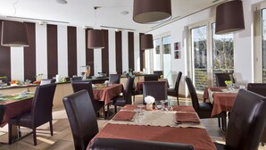 Een eetruimte met gestreepte wanden, grote ramen en moderne hanglampen.