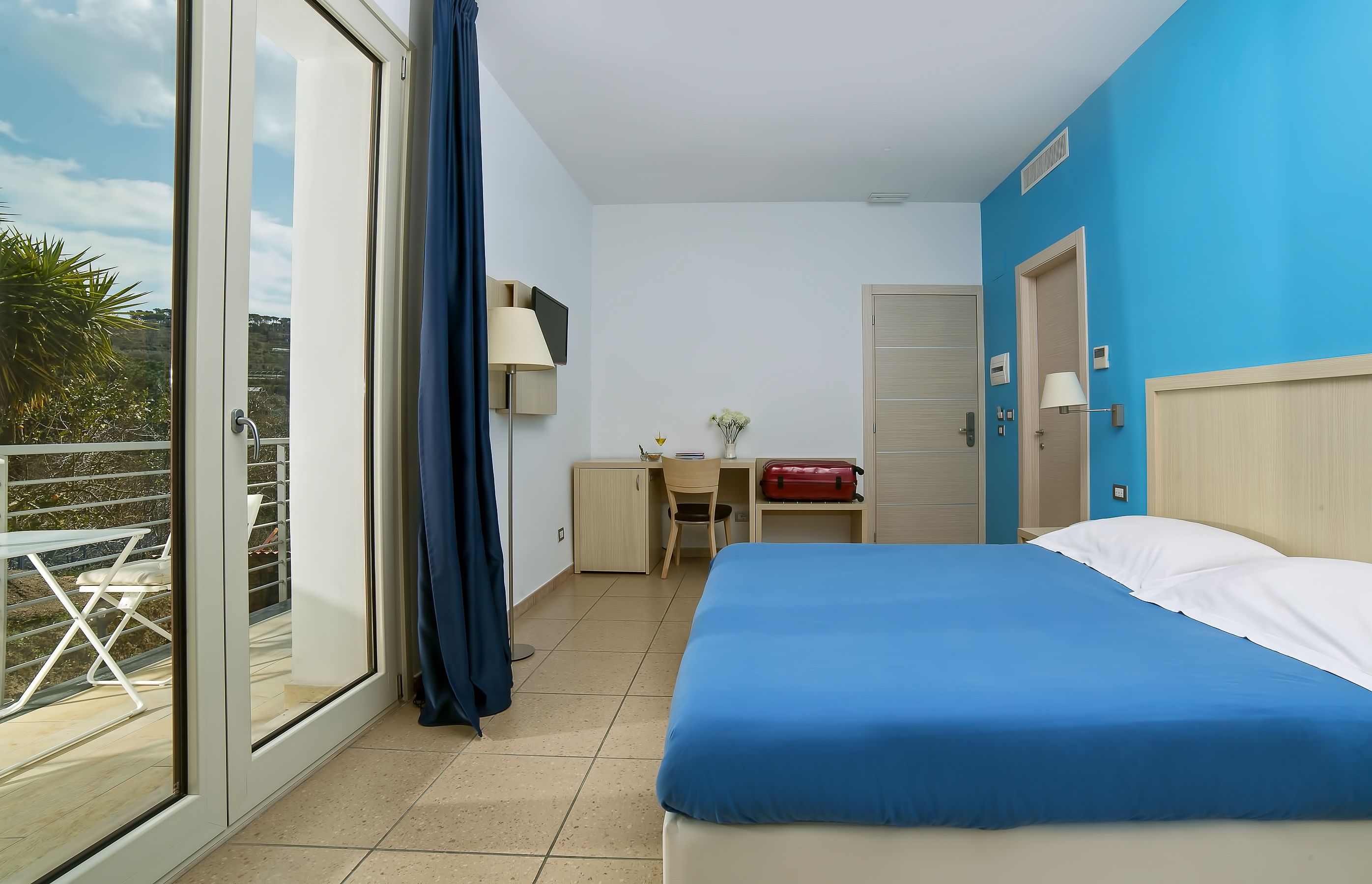 Ett hotellrum med en säng, ett skrivbord, en stol och utsikt över omgivningarna.