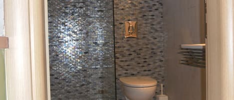 Un baño con cabina de ducha de vidrio, inodoro y lavamanos.