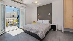 Een moderne slaapkamer met een groot bed, een schuifdeur naar een balkon en een klein nachtkastje.