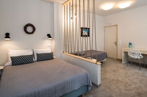 Un dormitorio con cama, lámparas de noche, una hamaca colgante, un escritorio y una silla.