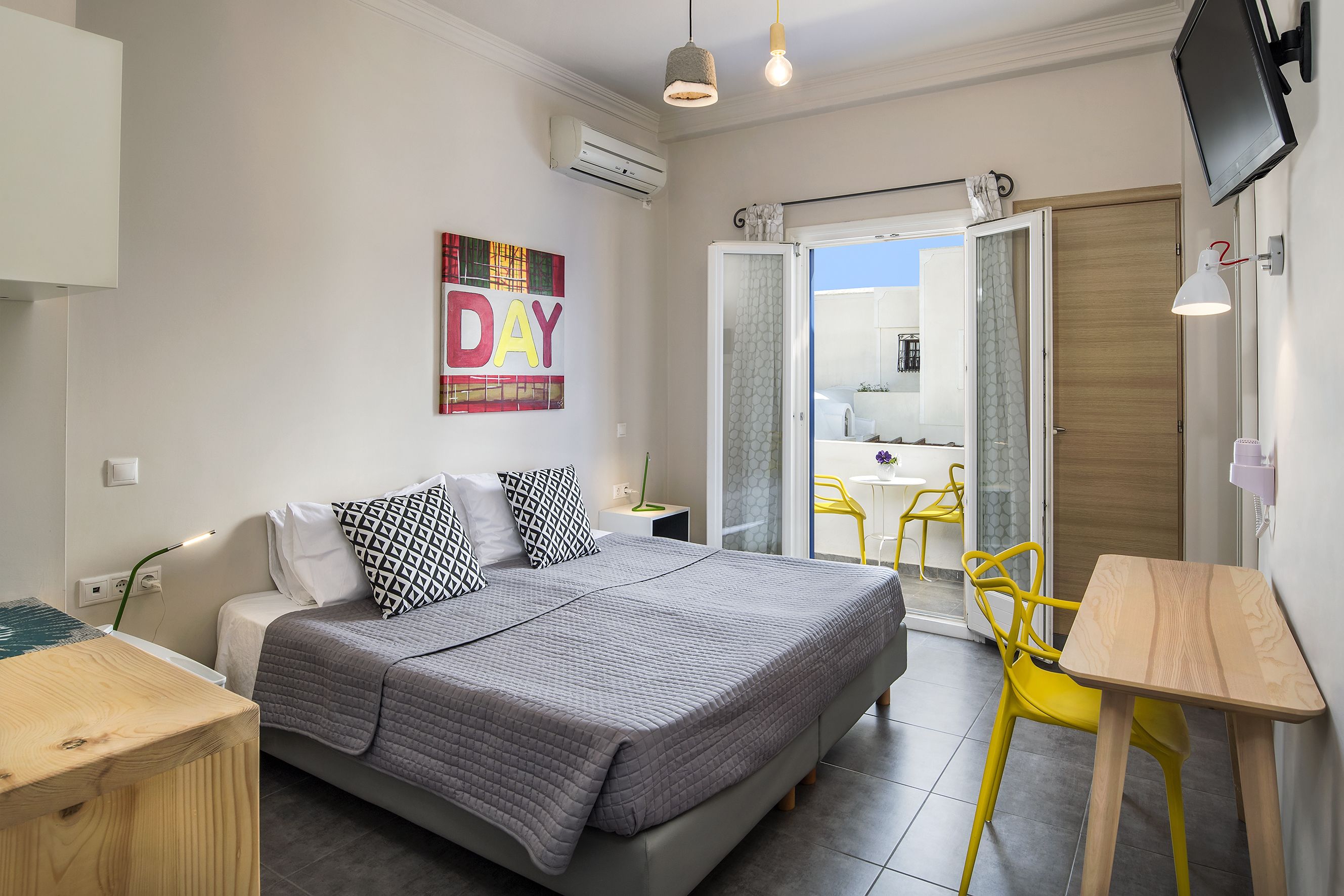A modern bedroom with a bed, bedside table, and a view to the outside.