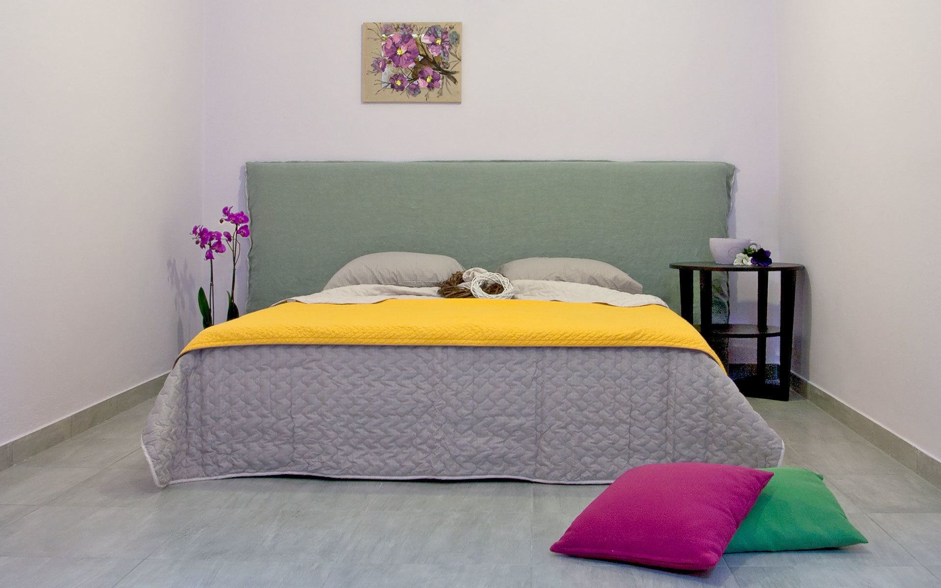 A bedroom with a bed, pillows, a bedside table, and a wall-mounted picture.