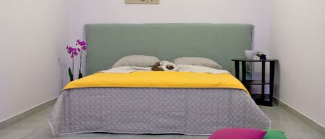 A bedroom with a bed, pillows, a bedside table, and a wall-mounted picture.