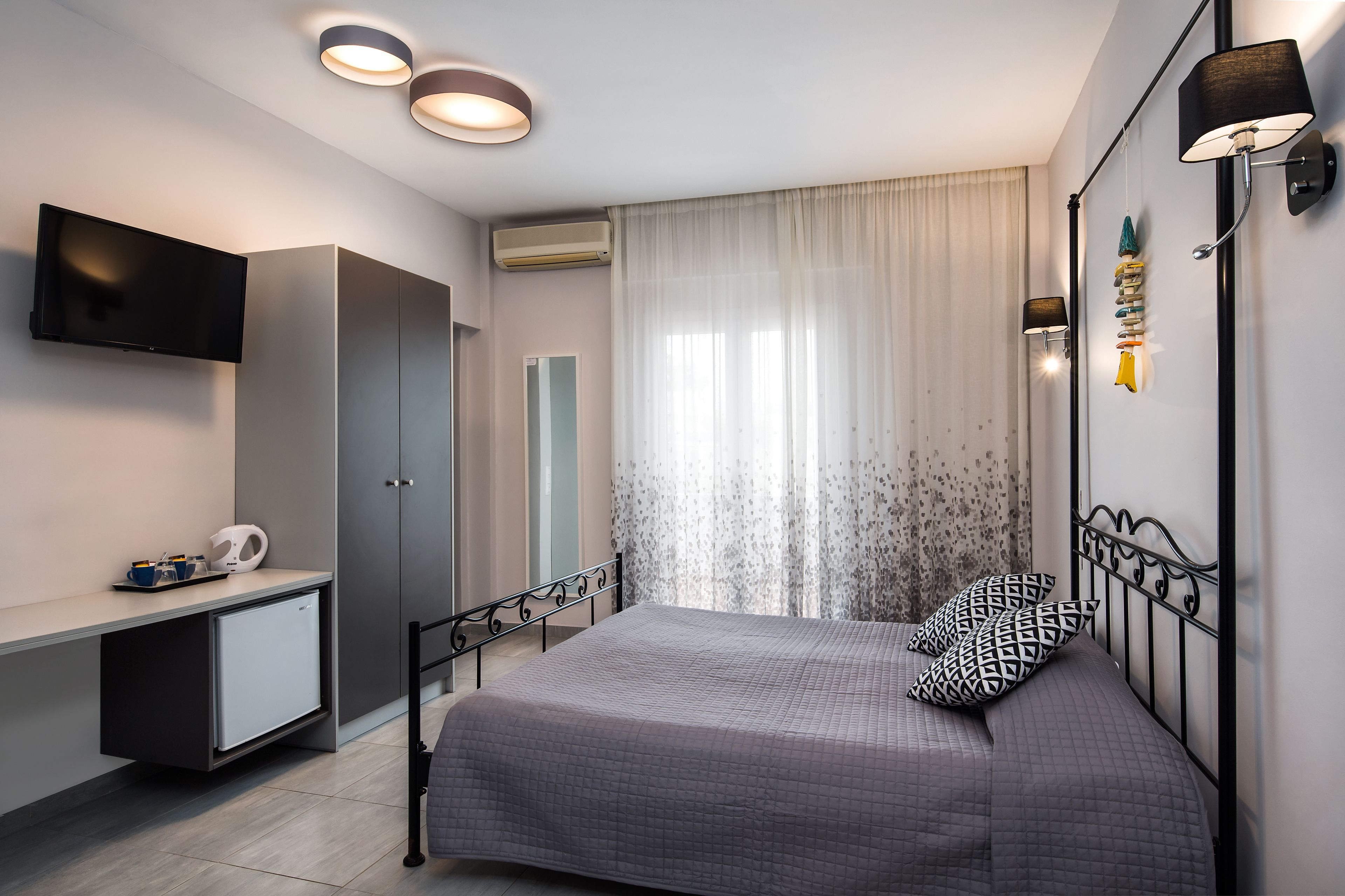 Een moderne slaapkamer met een bed, bureau, televisie en een kledingkast.