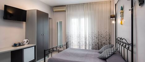 A modern bedroom with a bed, a desk, a TV, and a wardrobe.