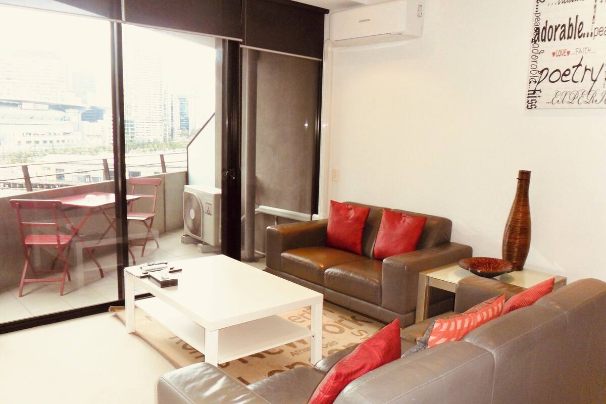A modern living room with a sofa, a coffee table, and a red fan.
