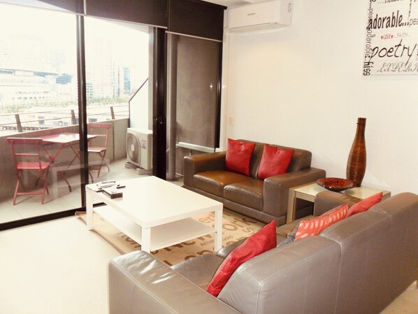 A modern living room with a sofa, a coffee table, and a red fan. - AKOM AT Docklands (Docklands)
