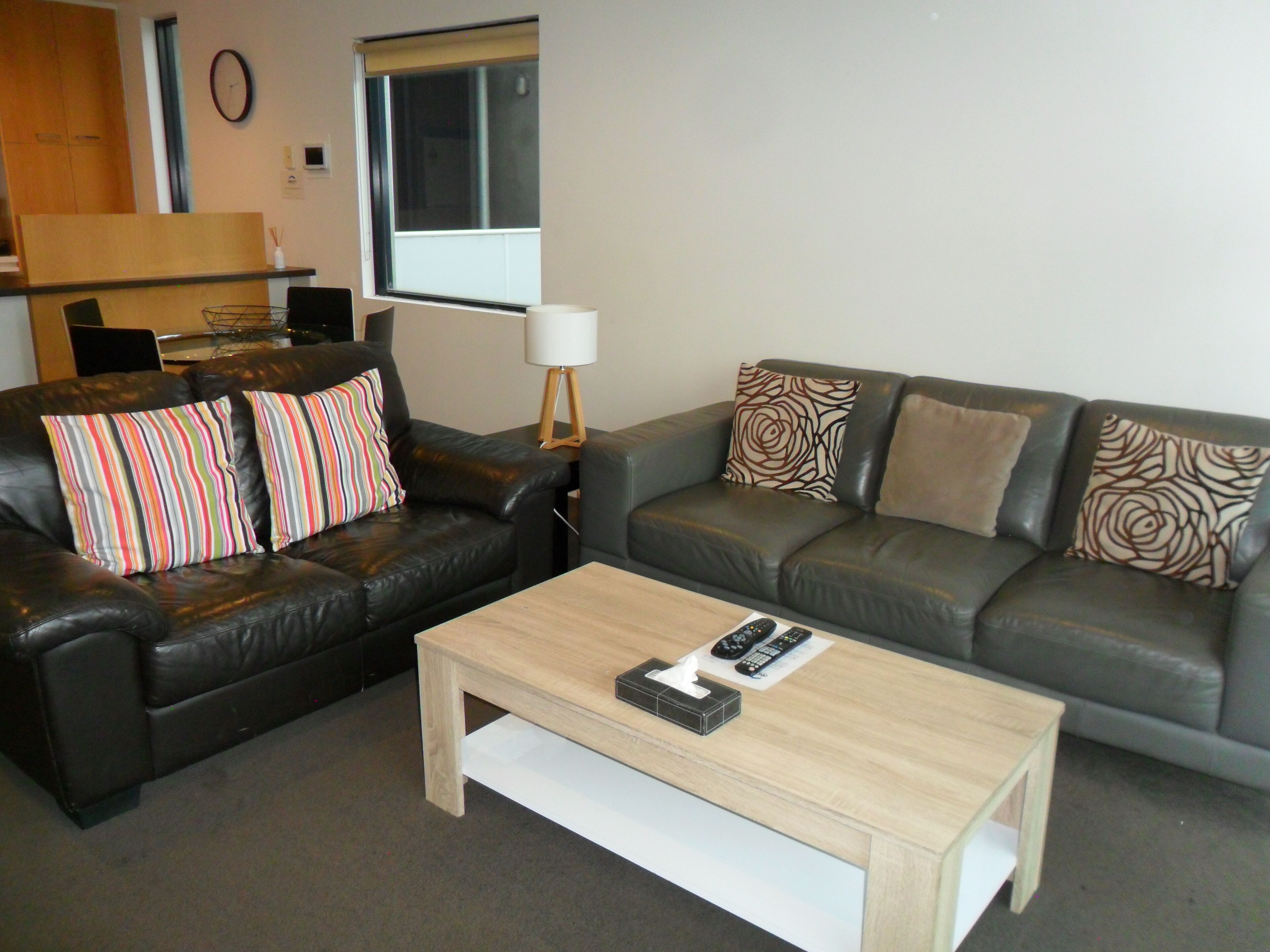 A living room with two leather sofas, a wooden coffee table, and a lamp.