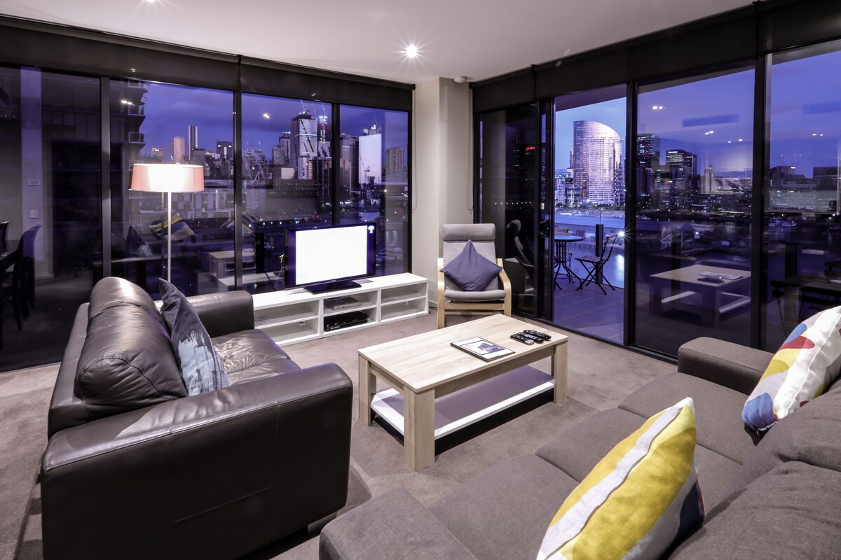 A modern living room with a city view, a sofa, a coffee table, and a TV.